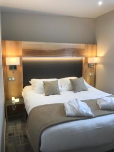 um quarto com uma grande cama branca e 2 almofadas em Hotel Le Cercle em Cherbourg en Cotentin