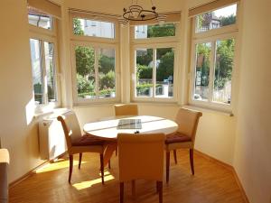 uma sala de jantar com mesa, cadeiras e janelas em Villa Weitblick em Eisenach