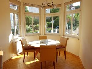 una sala da pranzo con tavolo, sedie e finestre di Villa Weitblick a Eisenach