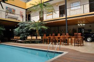 uma piscina no pátio de um hotel com mesa e cadeiras em Pousada Ilha Brazil em Ilhabela