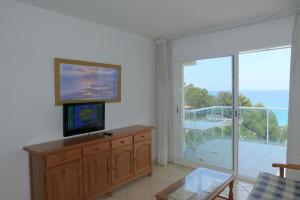 a living room with a tv and a sliding glass door at Rentalmar Gavina d'Or Apartamentos in Miami Platja