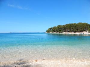 une plage avec de l'eau bleu clair et des arbres en arrière-plan dans l'établissement Mobile House on Drage Beach, à Pakoštane