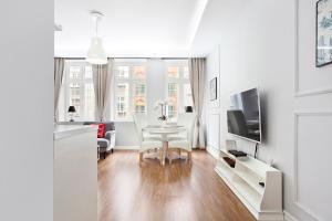 a white living room with a table and a tv at The Heart of Old Town Apartments in Gdańsk