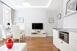 a white living room with a table and a tv at The Heart of Old Town Apartments in Gdańsk