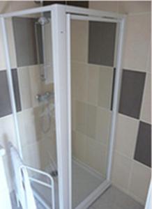 a glass shower door with a chair in a bathroom at La Ferme aux Biches in Commelle-Vernay