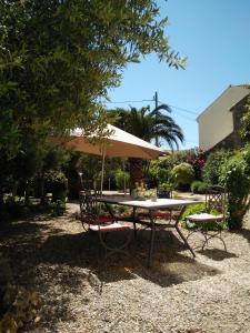 a picnic table and chairs with an umbrella at La Maison des Palmiers in Homps