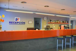 a reception counter in a restaurant with a person sitting at a desk at Hotel H2 Avila in Avila