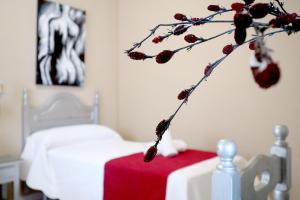 a bedroom with a bed and a branch with berries at Hostal Victoria in La Carlota