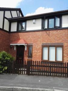 a red brick house with a wooden fence at RICHFLO Holiday Rentals in Manchester