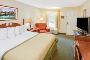 a hotel room with a large bed and a flat screen tv at Baymont by Wyndham Ozark in Ozark