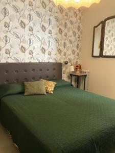 a bedroom with a bed with a green comforter at Aquila house in Catania