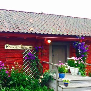 una casa roja con flores delante en Stora Djulö Vandrarhem en Katrineholm