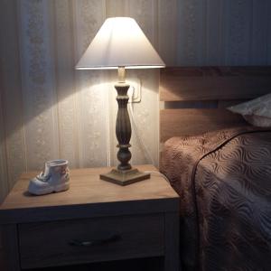 a lamp on a night stand next to a bed at Chance Apartment in Pärnu