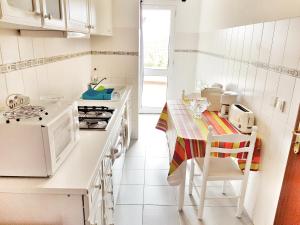 カニコにあるFalesia Apartment - Reis Magos Beachのキッチン(白い家電製品、テーブル、椅子付)