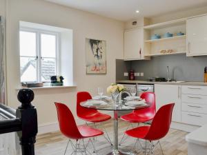 a kitchen with a table and red chairs in a kitchen at Pomegranate in Coleford
