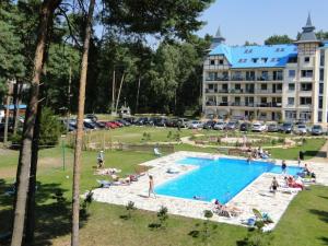a group of people sitting around a swimming pool next to a hotel at Blue Mare Apartamenty U Tomka in Łukęcin