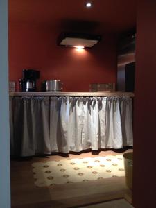 eine Küche mit weißen Vorhängen und einem Tisch mit einem Teppich in der Unterkunft Le voyage d'UBUNTU in Heiligenstein