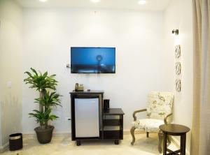 a living room with a chair and a tv on a wall at Hotel Presidente Las Tablas in Las Tablas