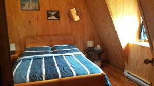 a bedroom with a bed in a wooden room at Grangette Entre Chiens et Loups in LʼAnse-Saint-Jean