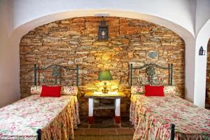 two beds in a room with a stone wall at Casa Saramago in Monsaraz
