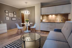 a living room with a couch and a table and a kitchen at Sosnowe Tarasy in Mielno
