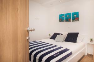 een wit bed met een blauwe en witte gestreepte deken bij Apartment Stella Maris in Kaprije