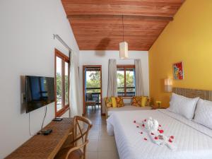 a bedroom with a white bed and a television at Pousada Paraíso do Forte in Praia do Forte