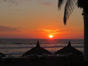 two beach umbrellas on the beach at sunset at Departamento de Lujo en Mazatlan in Mazatlán