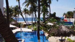 a swimming pool with palm trees and the ocean at Surf Olas Altas in Puerto Escondido +35 photos