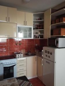 eine Küche mit weißen Schränken und einem weißen Kühlschrank in der Unterkunft Naissa Apartment in Niš