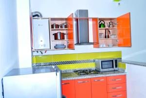 a kitchen with orange and yellow cabinets and a microwave at Appart Clim Wifi 700m de la Plage in Saïdia