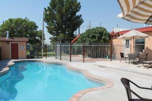 a swimming pool in a yard with chairs and a fence at Adobe Rose Boutique Inn in Artesia
