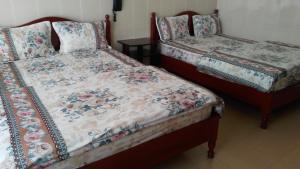 two beds sitting next to each other in a room at Nhà Nghỉ Du Lịch Nguyên Vũ in Da Lat