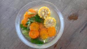 a glass bowl filled with carrots and flowers on a table at Bale Sembahulun Cottages & Tend in Sembalun Lawang