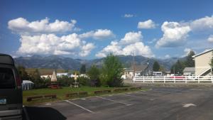 um parque de estacionamento com uma cerca branca e montanhas em Swiss Mountain Motel em Thayne