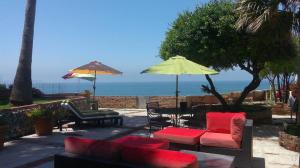 a patio with a couch and chairs and an umbrella at Hacienda Rancho Santini in Rosarito