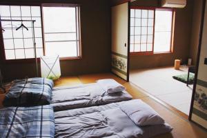 een kamer met 2 bedden in een kamer met ramen bij Guesthouse Ogawaya in Tanabe
