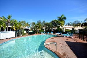 a large swimming pool with chairs and palm trees at Broome in Broome