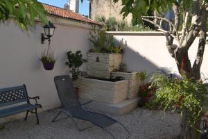 a chair sitting next to a wall with potted plants at la PASSERONNE in Barbentane