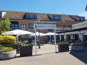 KomfortHotel Grossbeeren - Stadt-Gut-Hotel في غروسبيرن: فندق به طاولات ومظلات في ساحة الفناء