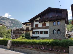 a house in the mountains with a fence and flowers at Appartamenti dei Giardini in Courmayeur