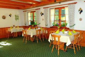 ein Esszimmer mit Tischen, Stühlen und Fenstern in der Unterkunft Pension Löffelschmiede in Lenzkirch