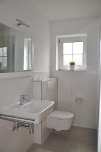 a white bathroom with a sink and a toilet at Haus Antonie 1. Etage in Dahme