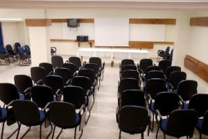 una habitación con filas de sillas y una mesa blanca en Hotel Obino Bagé, en Bagé