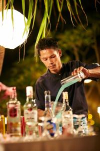 a man pouring a drink into a table with alcohol at Vacation Village Phra Nang Lanta - SHA Extra Plus in Ko Lanta