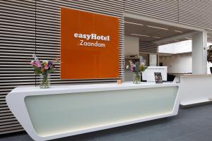 a reception desk in a lobby with flowers on it at easyHotel Amsterdam Zaandam in Zaandam