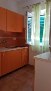 eine Küche mit orangefarbenen Schränken und einem Fenster in der Unterkunft Apartments Jaksic in Postira + 112 Fotos