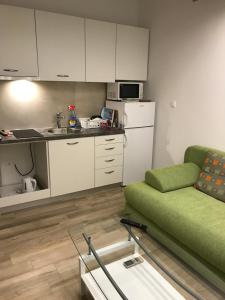 a living room with a green couch and a kitchen at Apartment Kiara in Omišalj