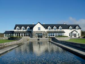 ein großes Haus mit einem Teich davor in der Unterkunft Westport Country Lodge Hotel in Westport