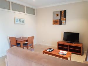ein Wohnzimmer mit einem Sofa, einem TV und einem Tisch in der Unterkunft Vine Inn Barossa in Nuriootpa